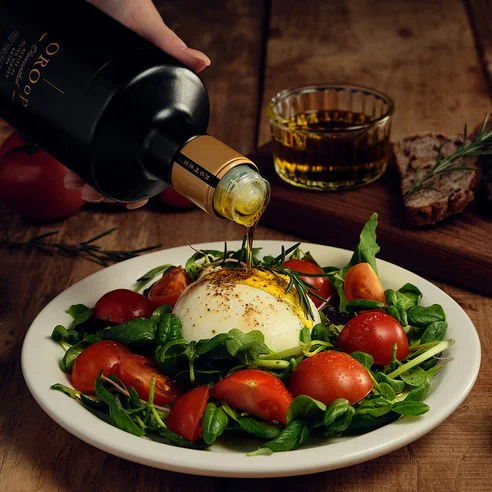 신선한 샐러드에 올리브 오일을 뿌리는 모습